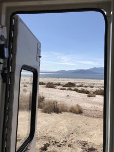 An open van door looking out into a desert landscape with mountains in the distance.