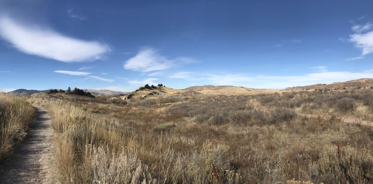 Prairie grassland, blue skies; rocks sticking up out of the ground like a backbone